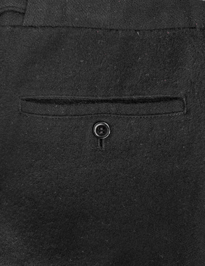 Close-up of a dark gray suit pocket with a button on a matching fabric background