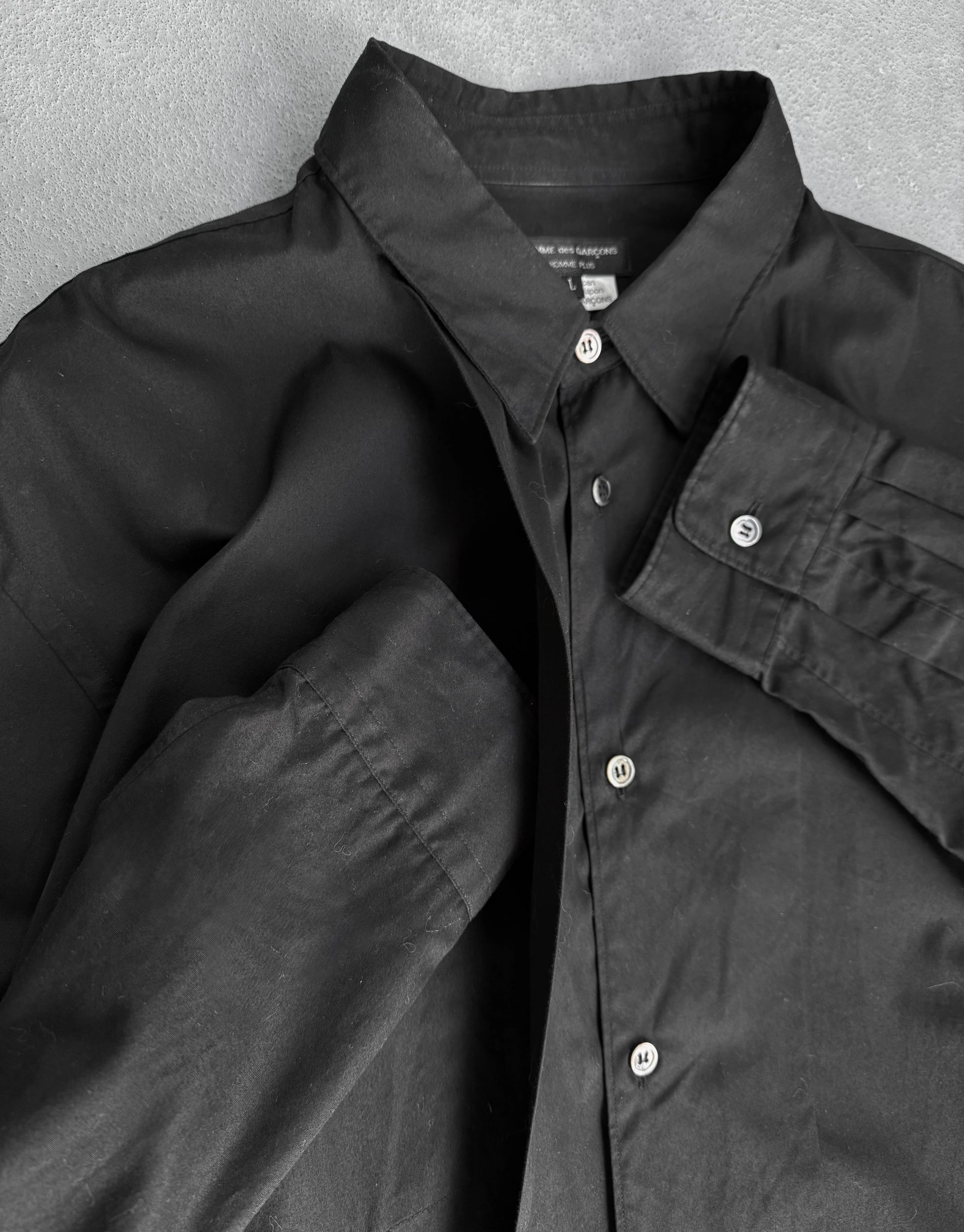 Black shirt with button details on a textured gray background