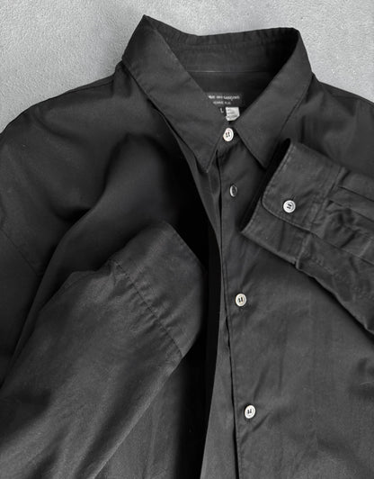Black shirt with button details on a textured gray background