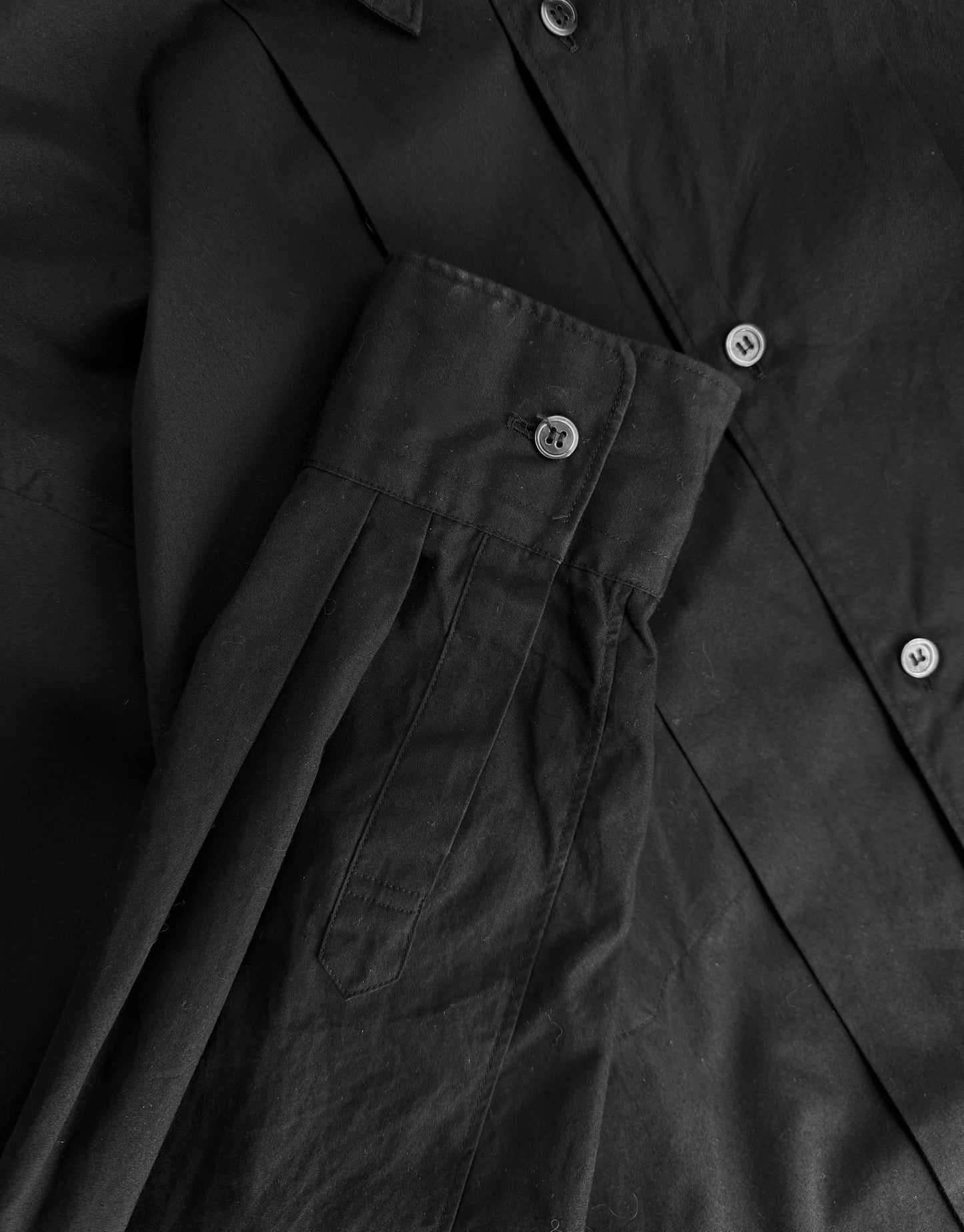 Close-up of a black coat with buttons and a pocket