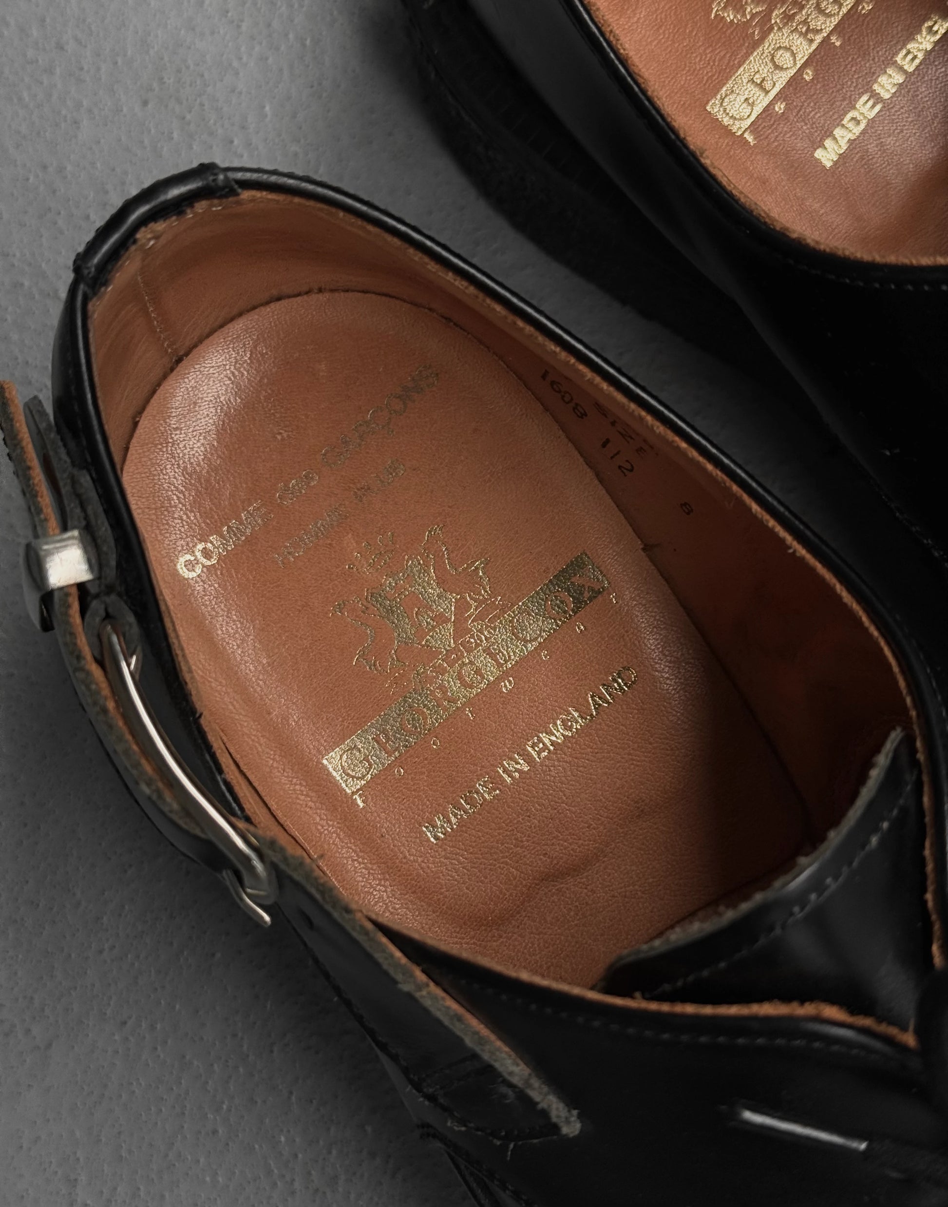 Close-up of a brown leather insole with gold text on a black shoe.