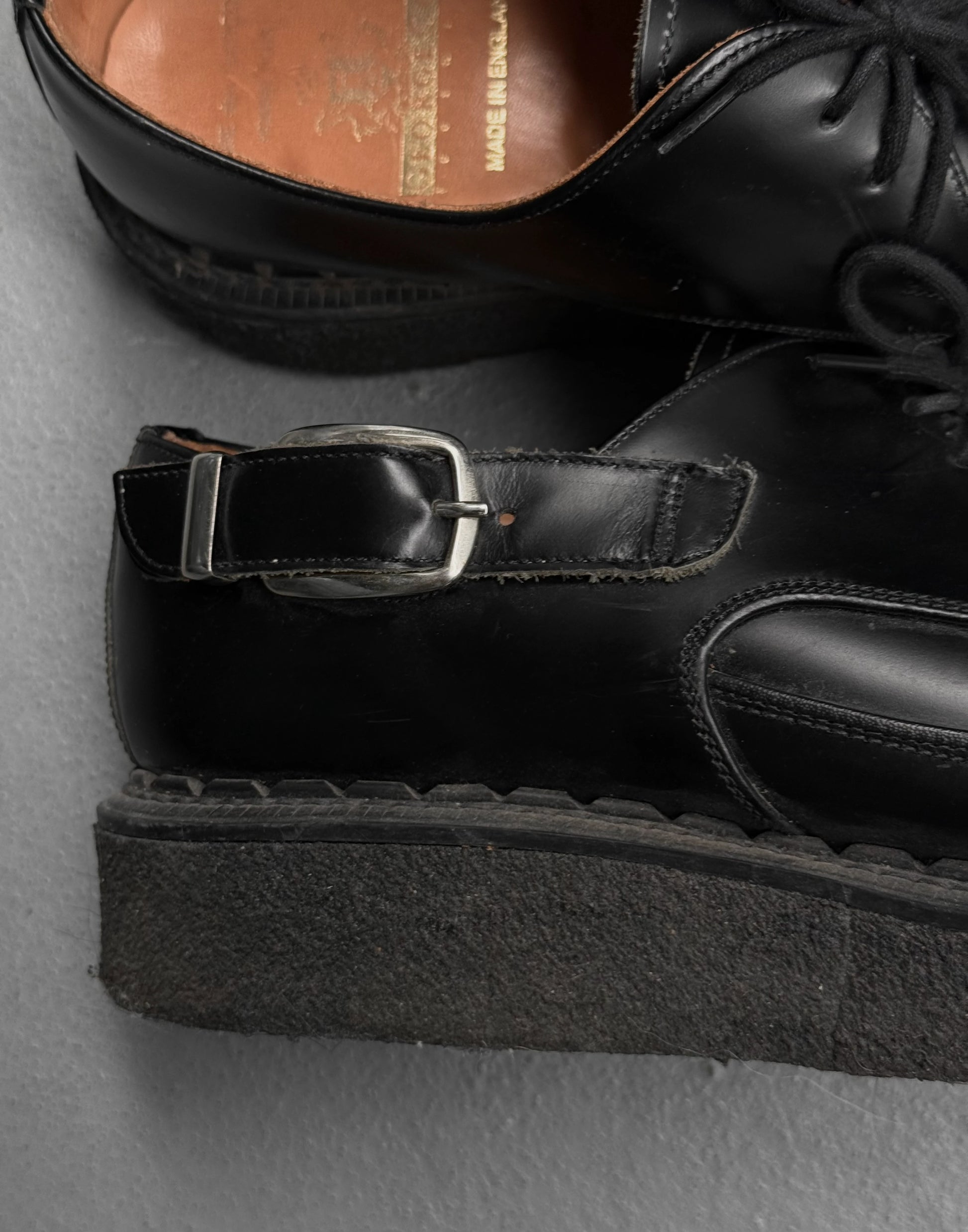 Black leather shoes with a buckle on a gray surface