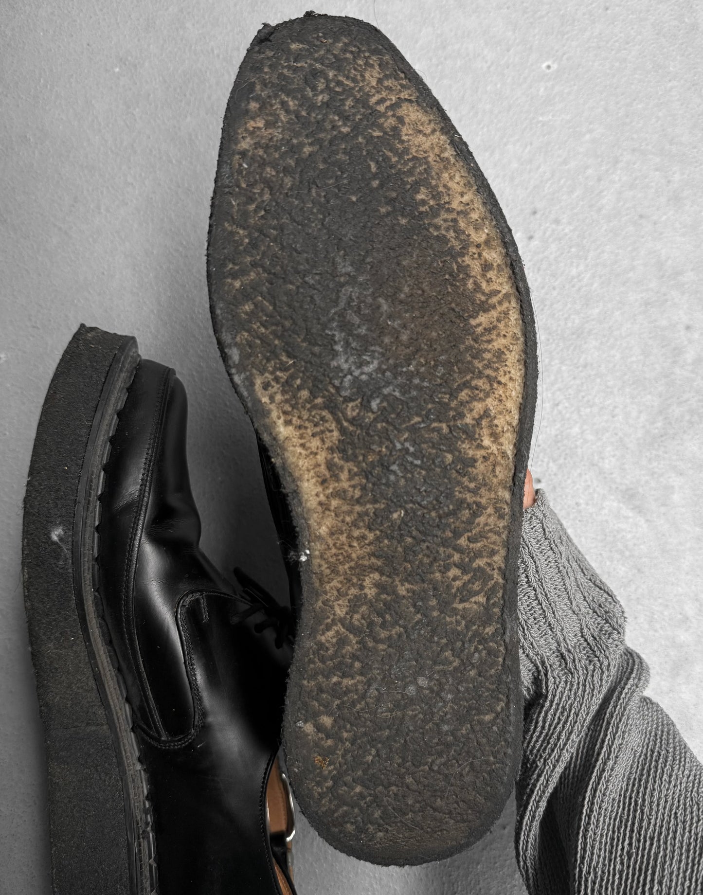 Close-up of a worn black shoe sole on a gray surface