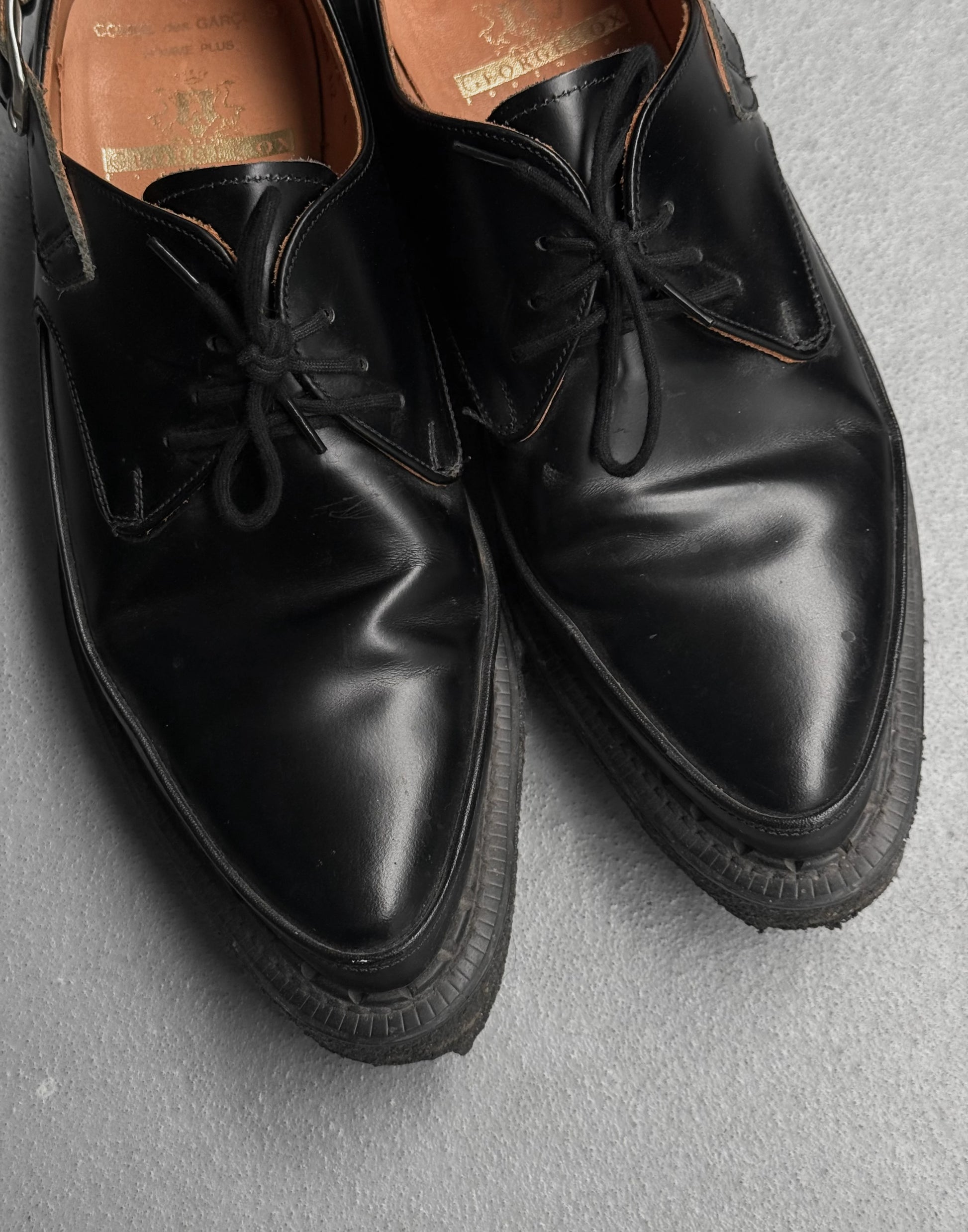 Pair of black leather shoes on a gray surface