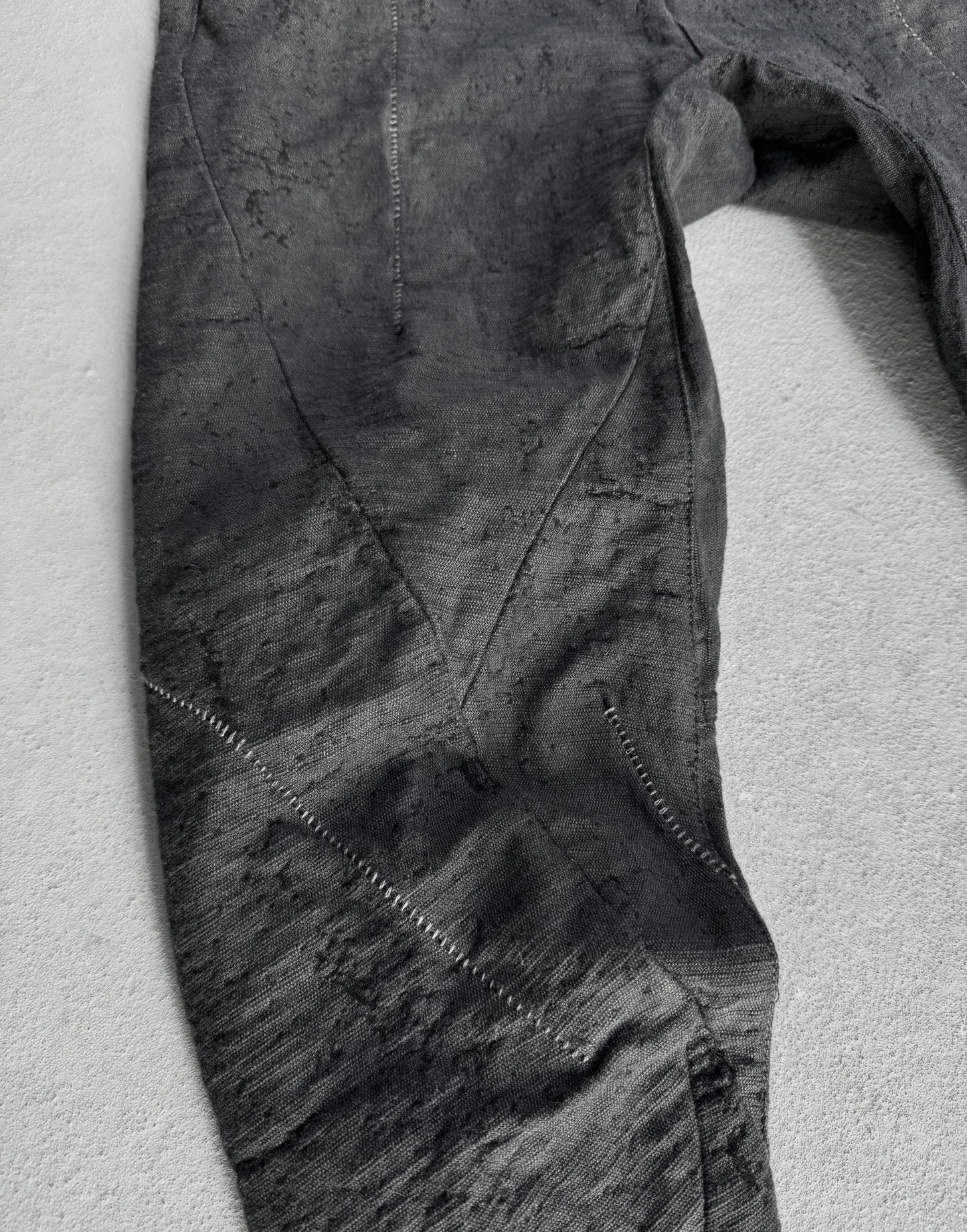 Close-up of a textured gray fabric with visible stitching on a light gray background