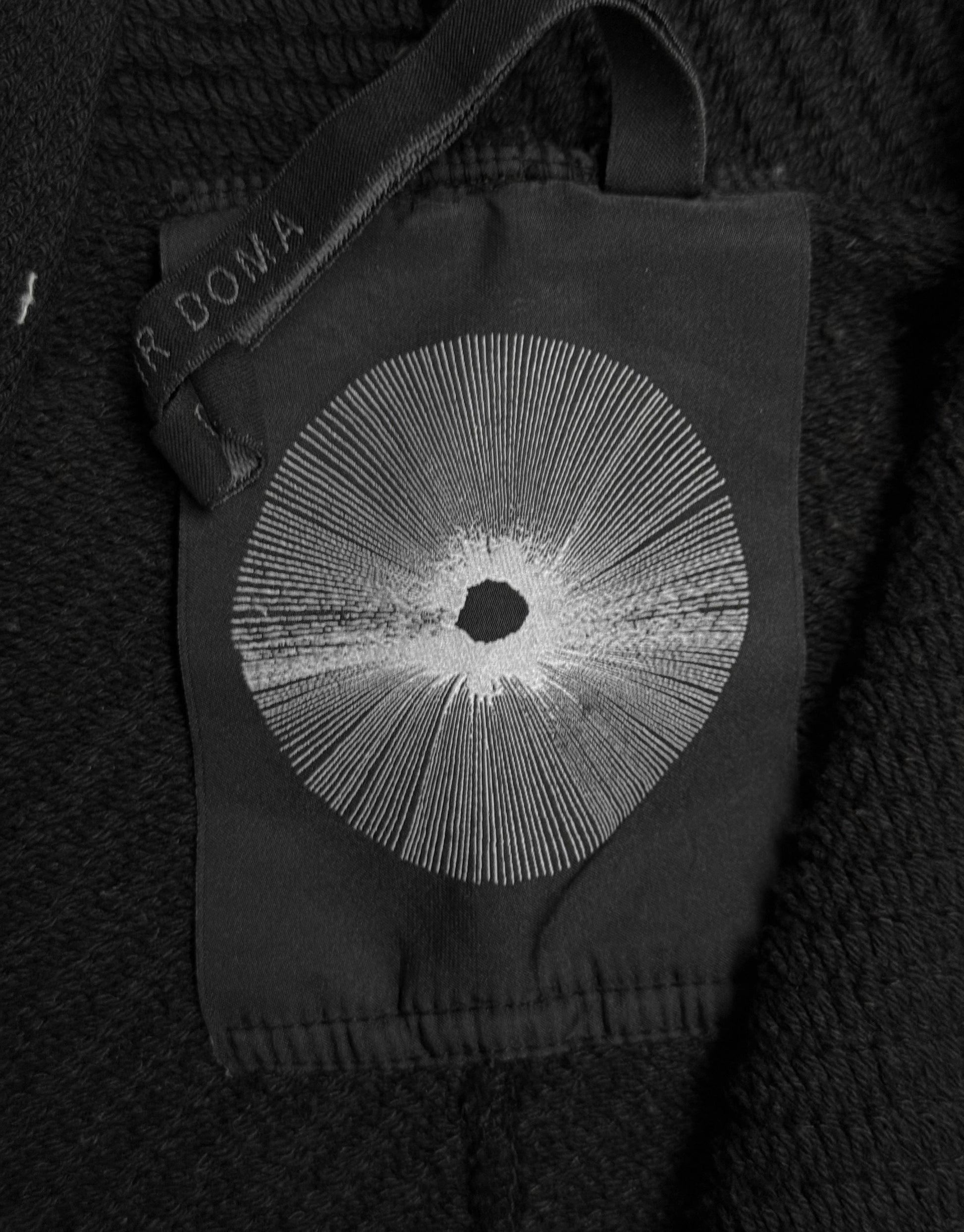 Black glove with a central circular design on a dark textured background