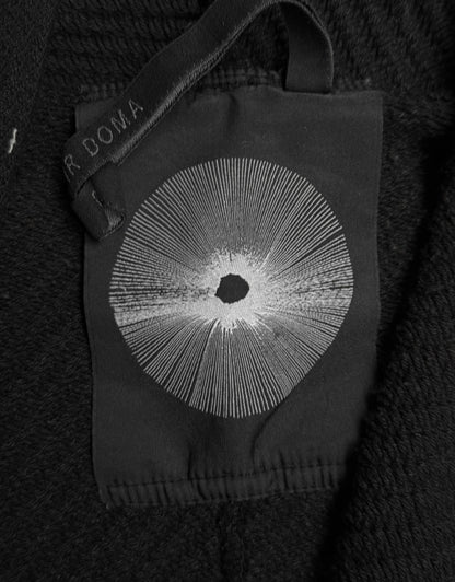 Black glove with a central circular design on a dark textured background