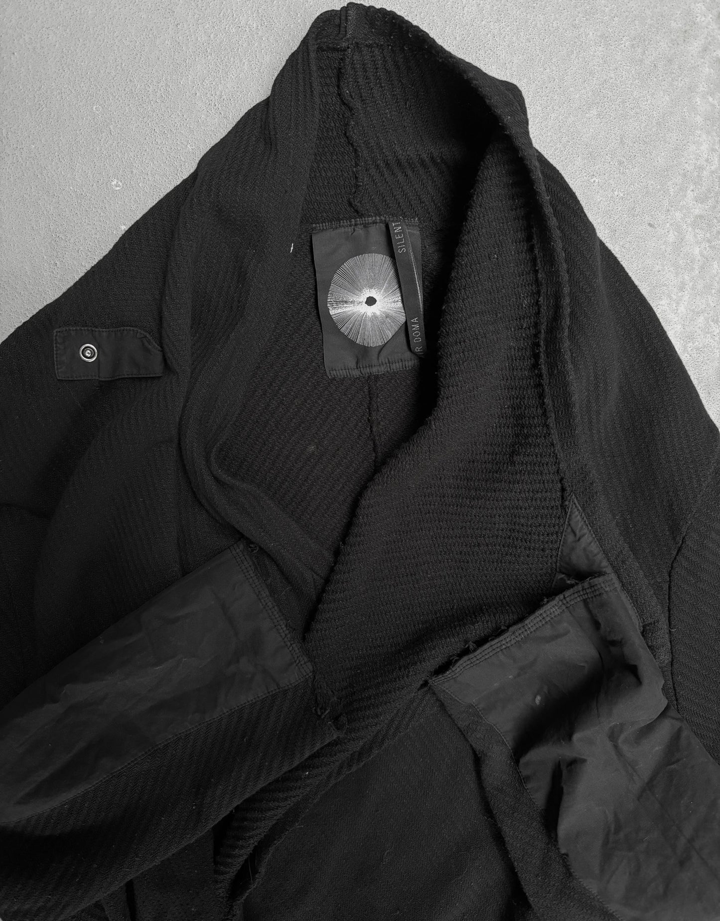 Close-up of a black jacket with a brand label on a gray background