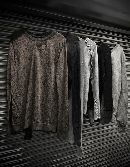 Row of sweaters hanging on a metal rack with a textured wall background