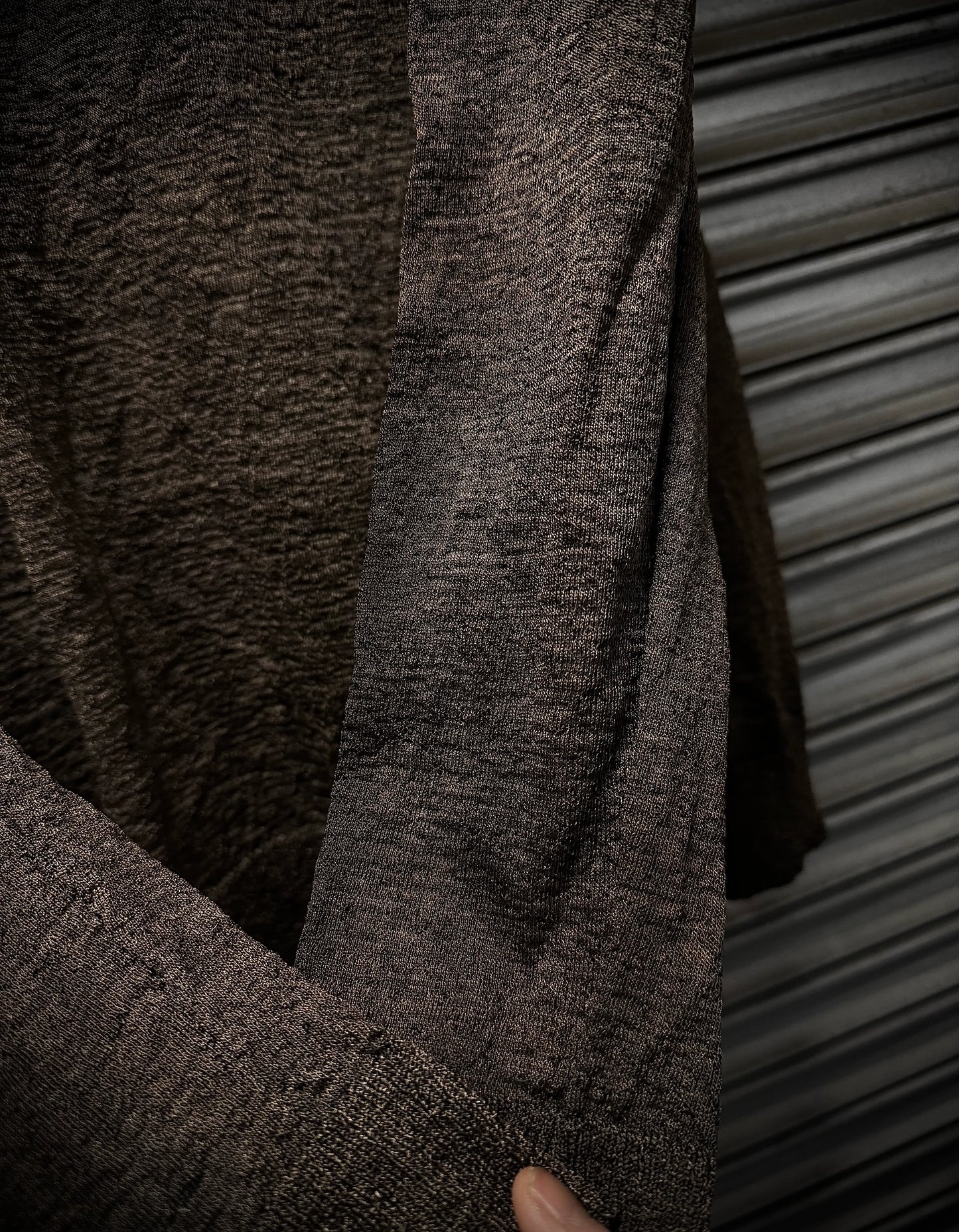 Close-up of a textured brown sweater against a metallic background