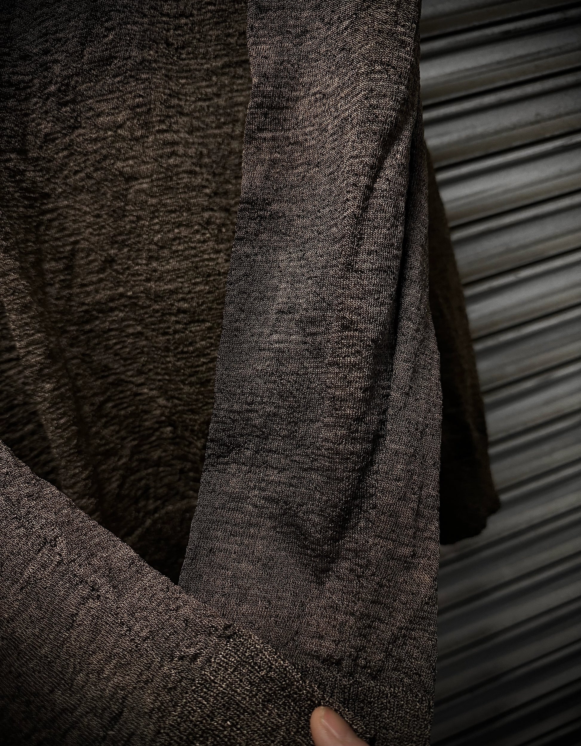 Close-up of a textured brown sweater against a metallic background