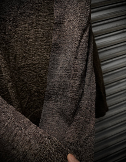 Close-up of a textured brown sweater against a metallic background