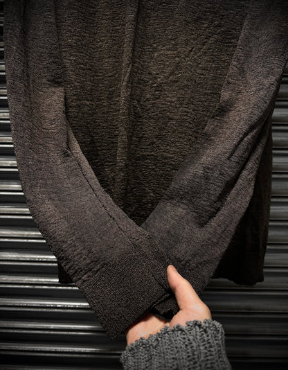Close-up of a person wearing a dark gray sweater with a blurred background