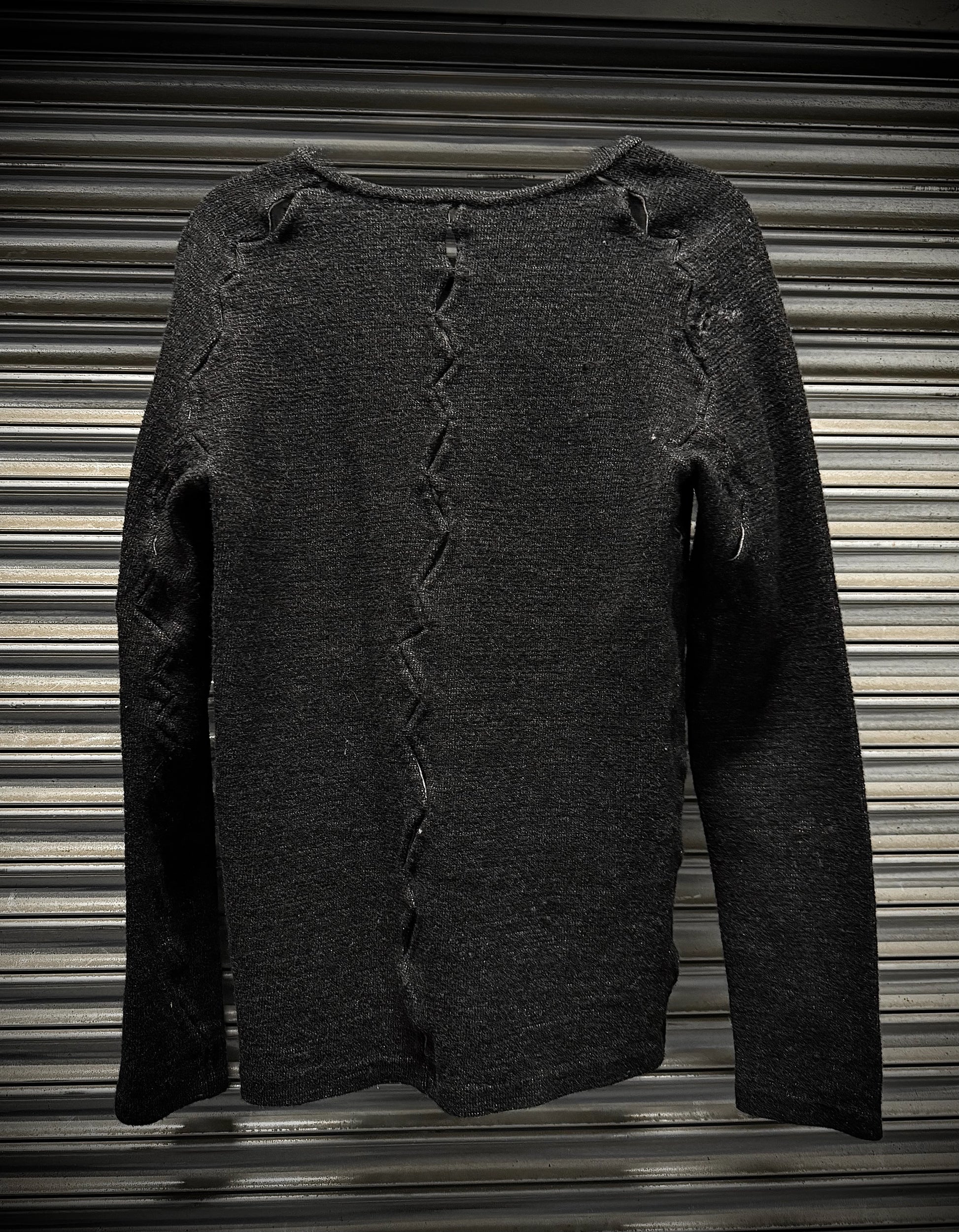 Dark gray sweater with distressed details on a corrugated metal background