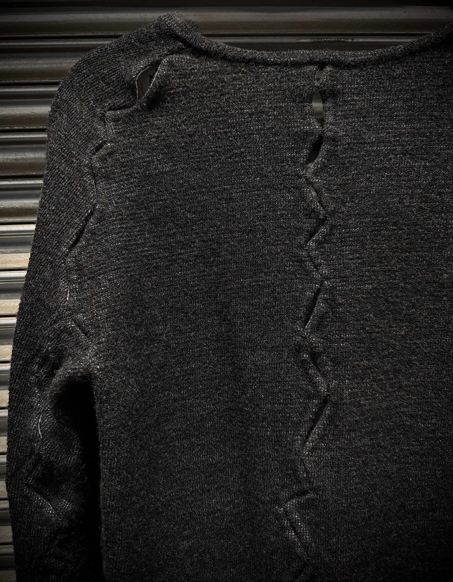 Dark gray sweater with textured pattern on a metallic surface