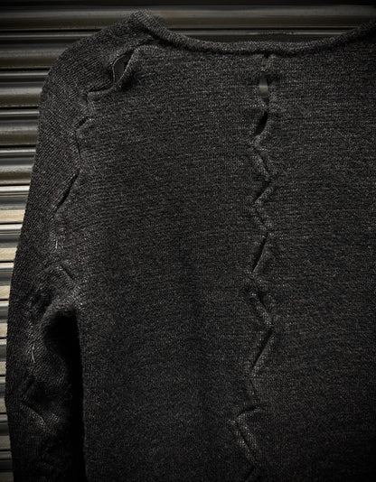 Dark gray sweater with textured pattern on a metallic surface