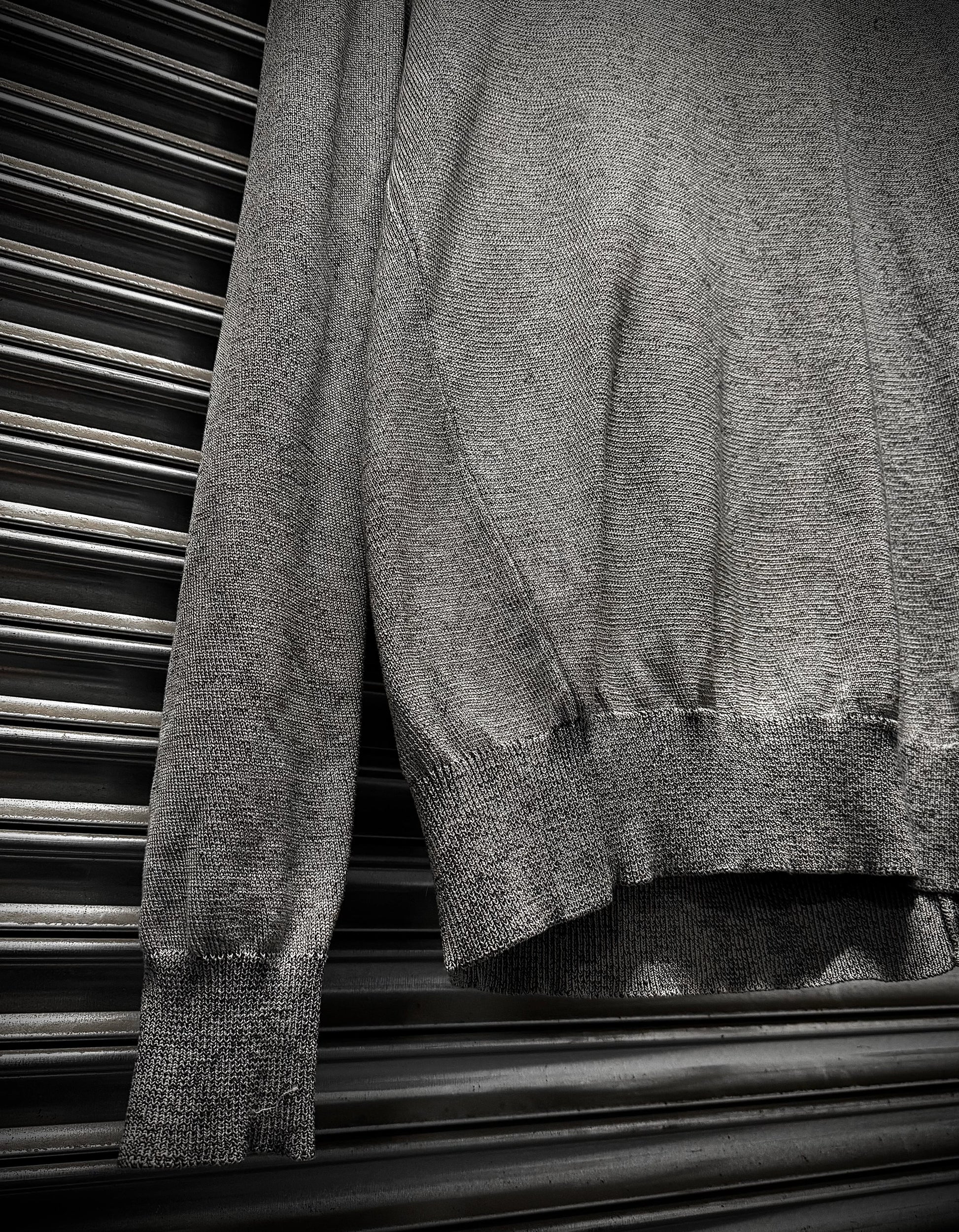 Gray sweater draped over a metallic surface