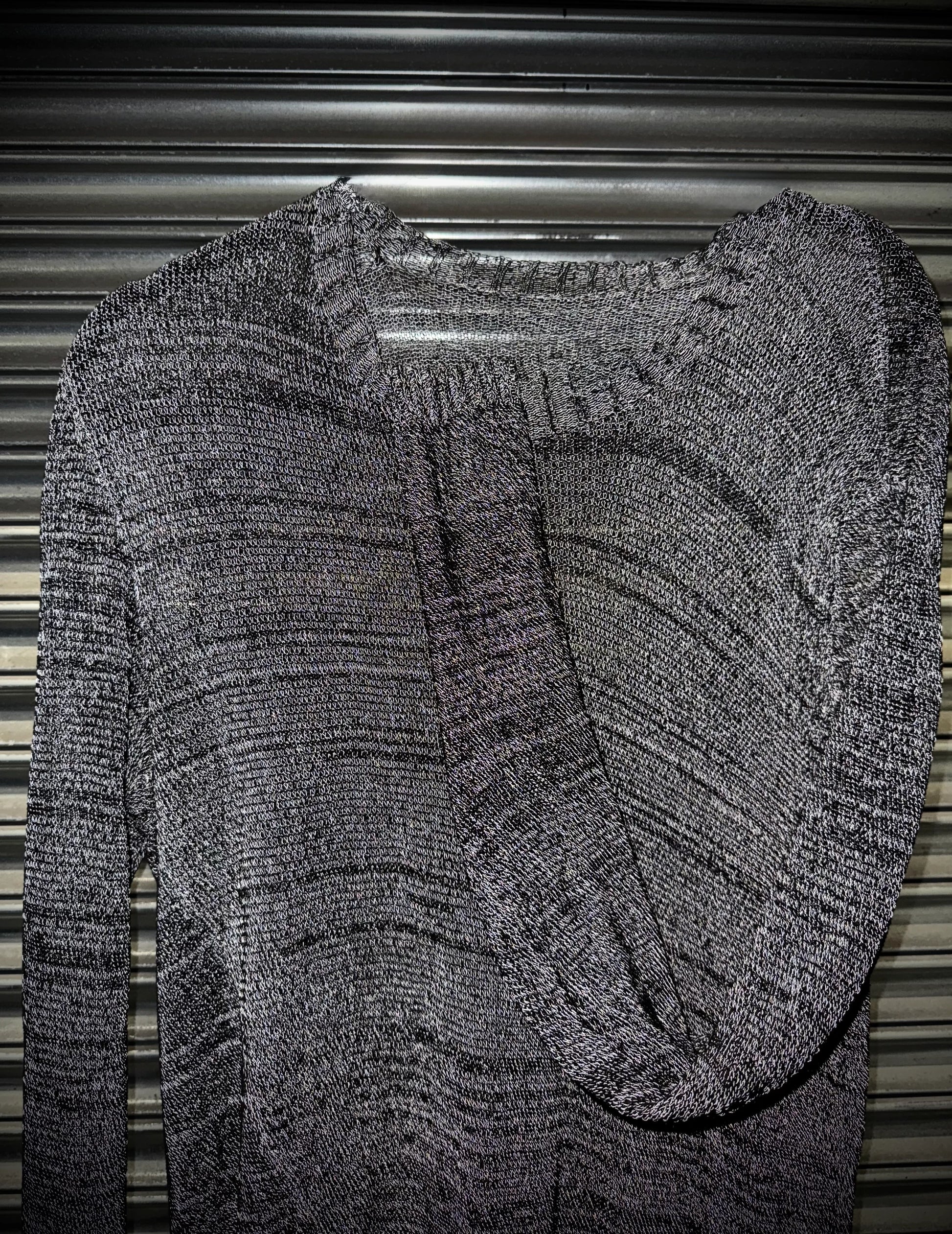 Gray textured sweater on a hanger against a metallic background