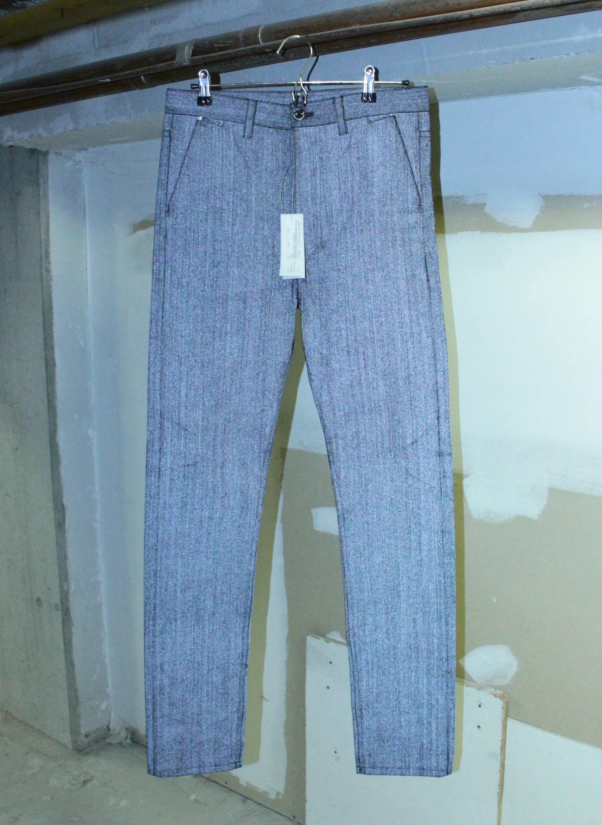 Reflective jeans hanging on a hanger against a plain background
