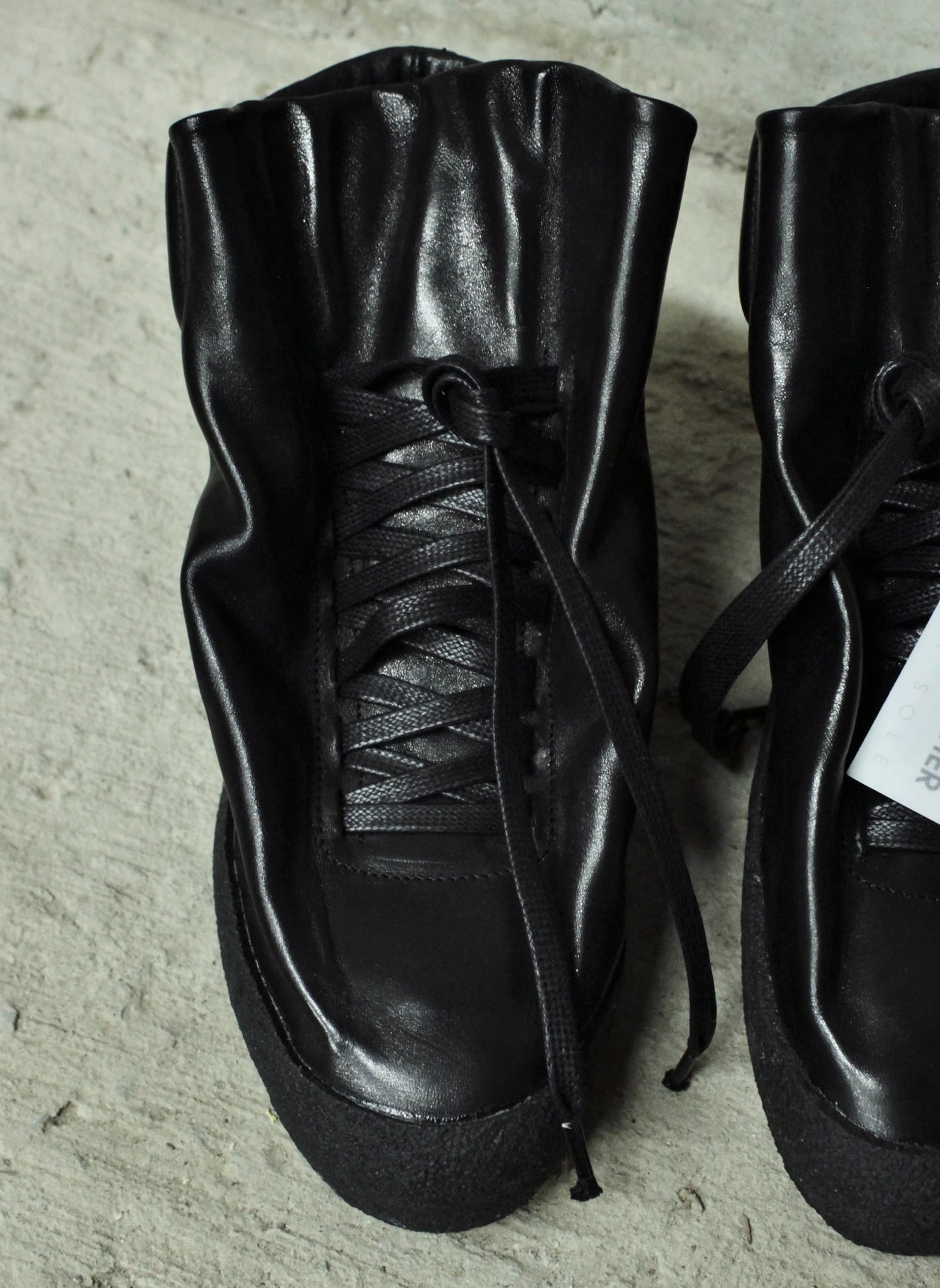 Pair of black leather boots on a textured surface