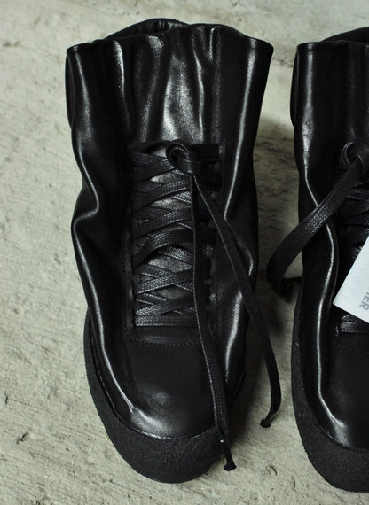 Pair of black leather boots on a textured surface