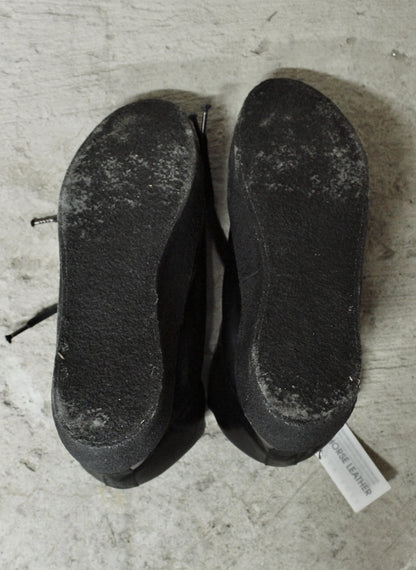 Pair of worn black shoes on a concrete floor