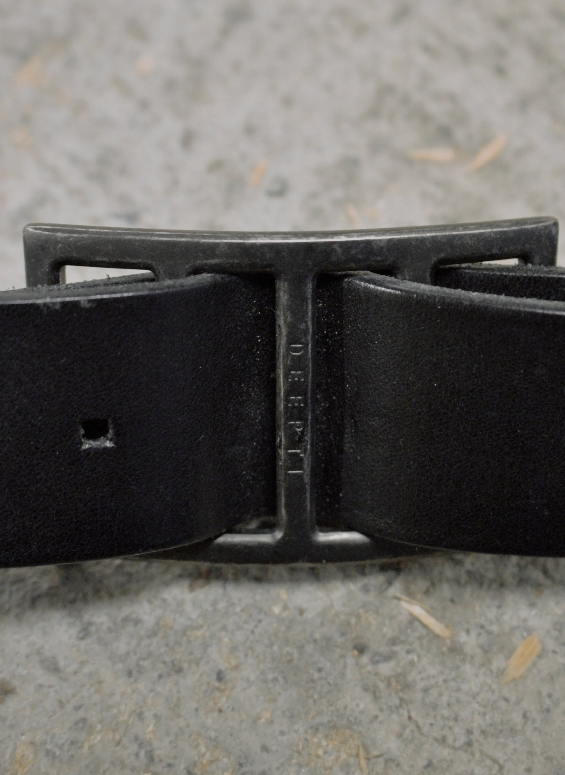 Black belt with a metal buckle on a textured surface