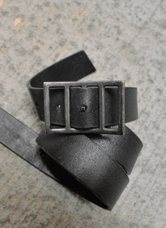 Black leather belt with a rectangular buckle on a textured surface