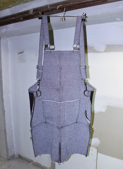 reflective denim overalls hanging on a hook against a white wall.