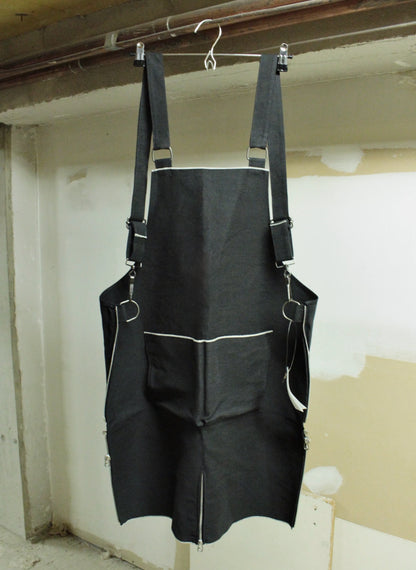 Black apron hanging on a hook against a plain wall.