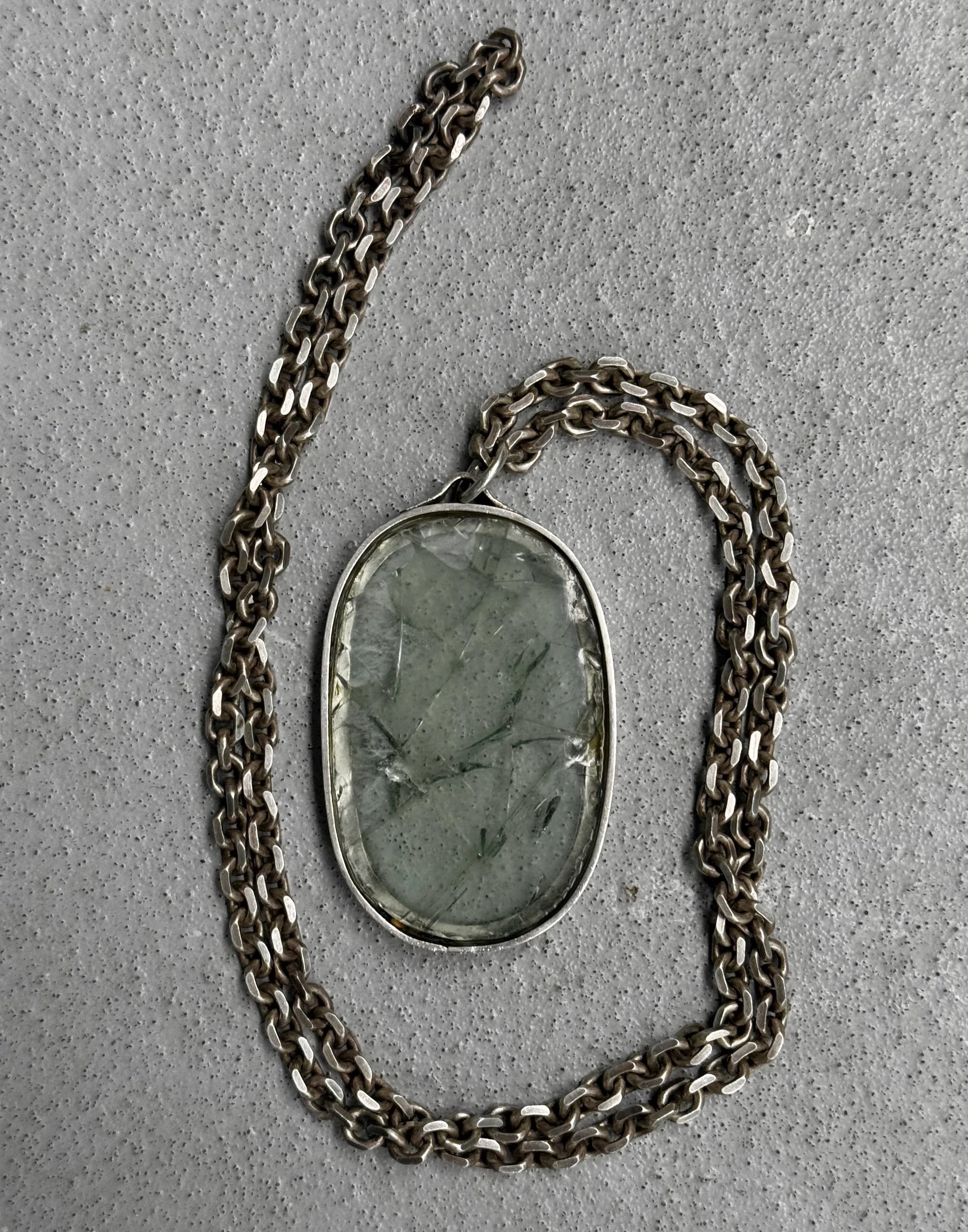 Necklace with a green stone pendant on a gray surface