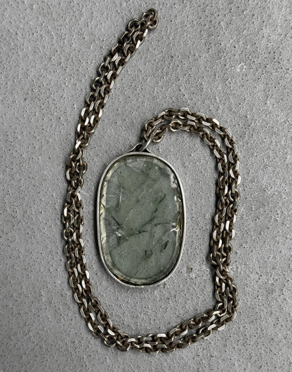 Necklace with a green stone pendant on a gray surface