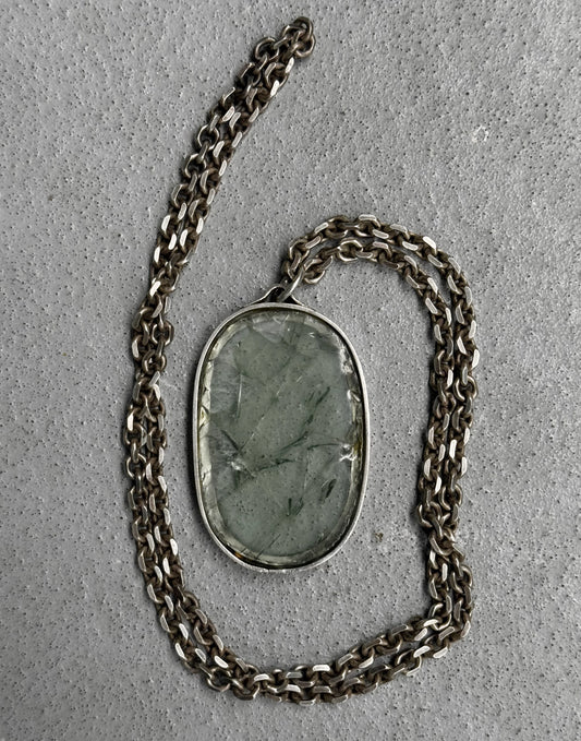Necklace with a green stone pendant on a gray surface