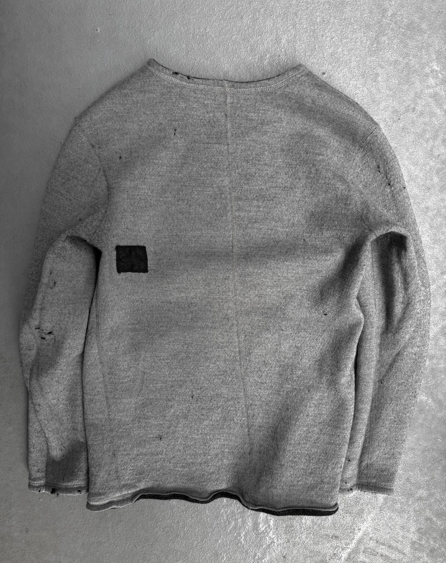 Gray sweater with a black patch on a gray background