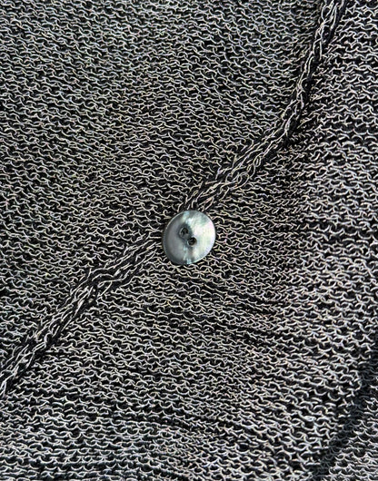 Close-up of a textured surface with a chain and round object.