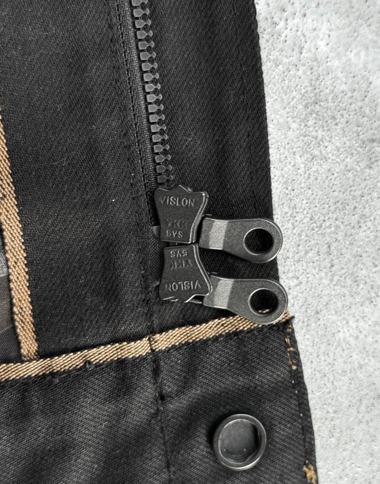 Close-up of a zipper on a black denim jacket with a visible brand label.