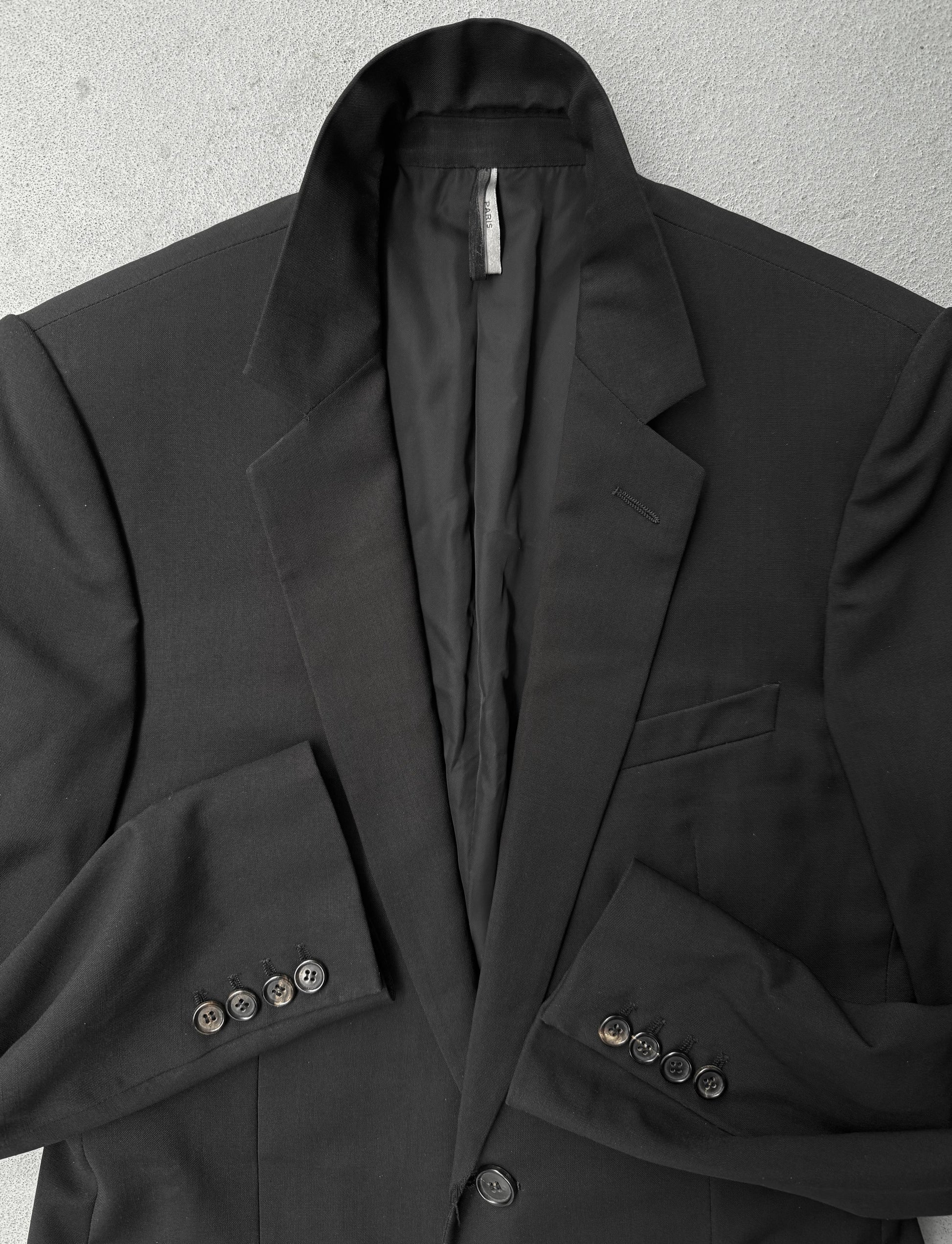 Black blazer with button details on a textured gray background
