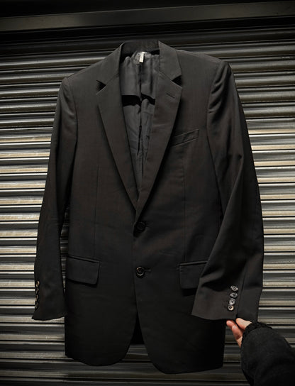 Black suit jacket held by a hand against a metallic shutter background