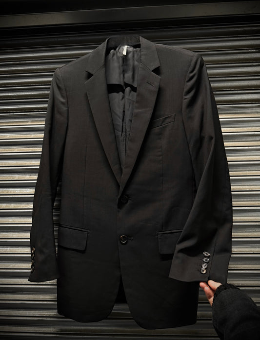Black suit jacket held by a hand against a metallic shutter background