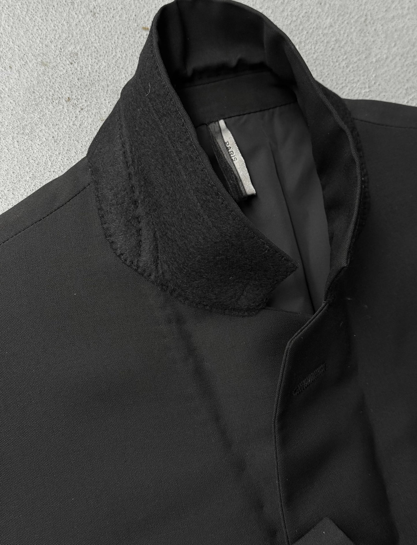 Close-up of a black coat with a textured collar on a light gray background
