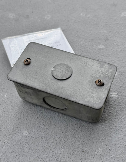 Metal box with screws on a gray concrete surface