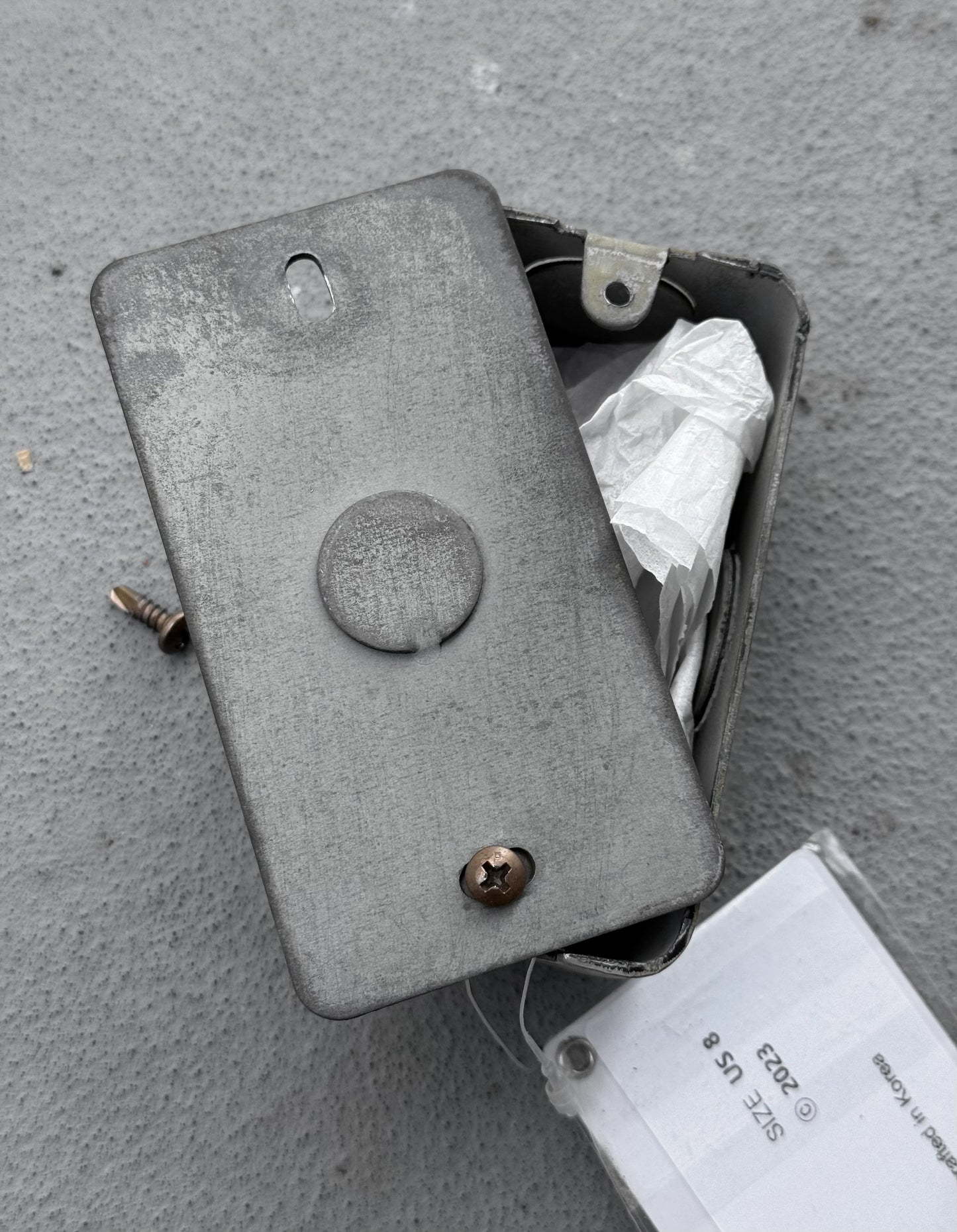 Metal box with screws on a gray surface