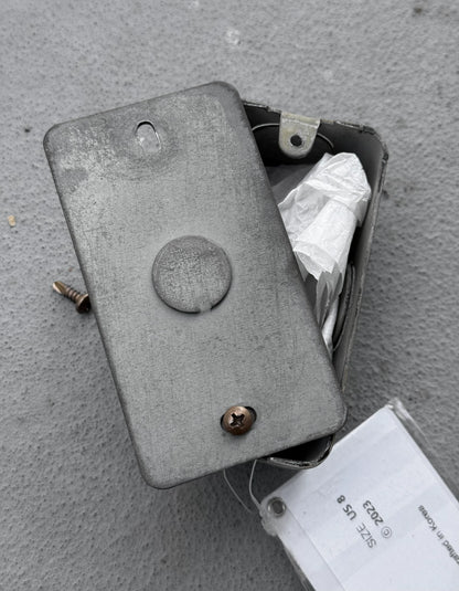 Metal box with screws on a gray surface