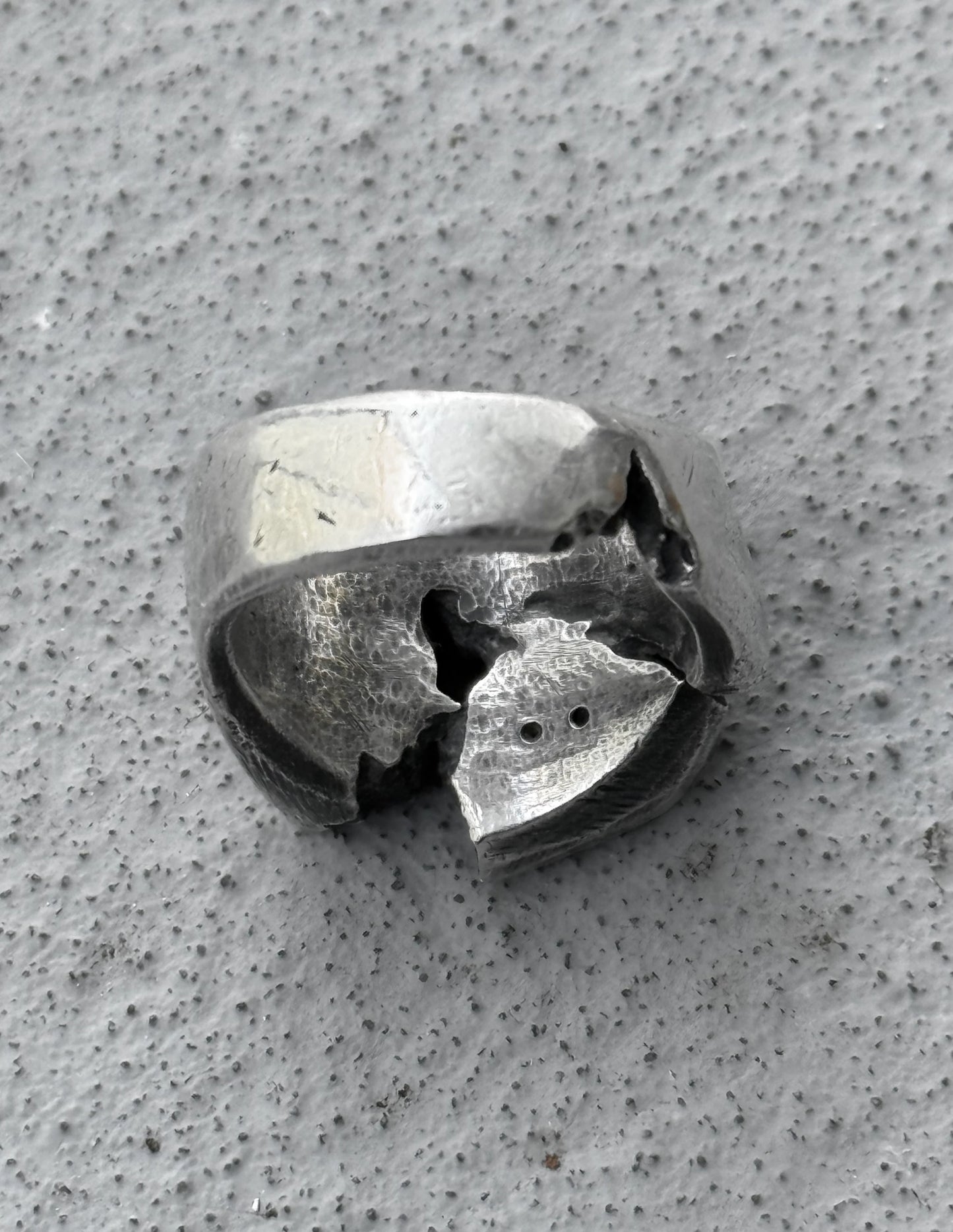 Silver ring with a unique design on a textured gray surface