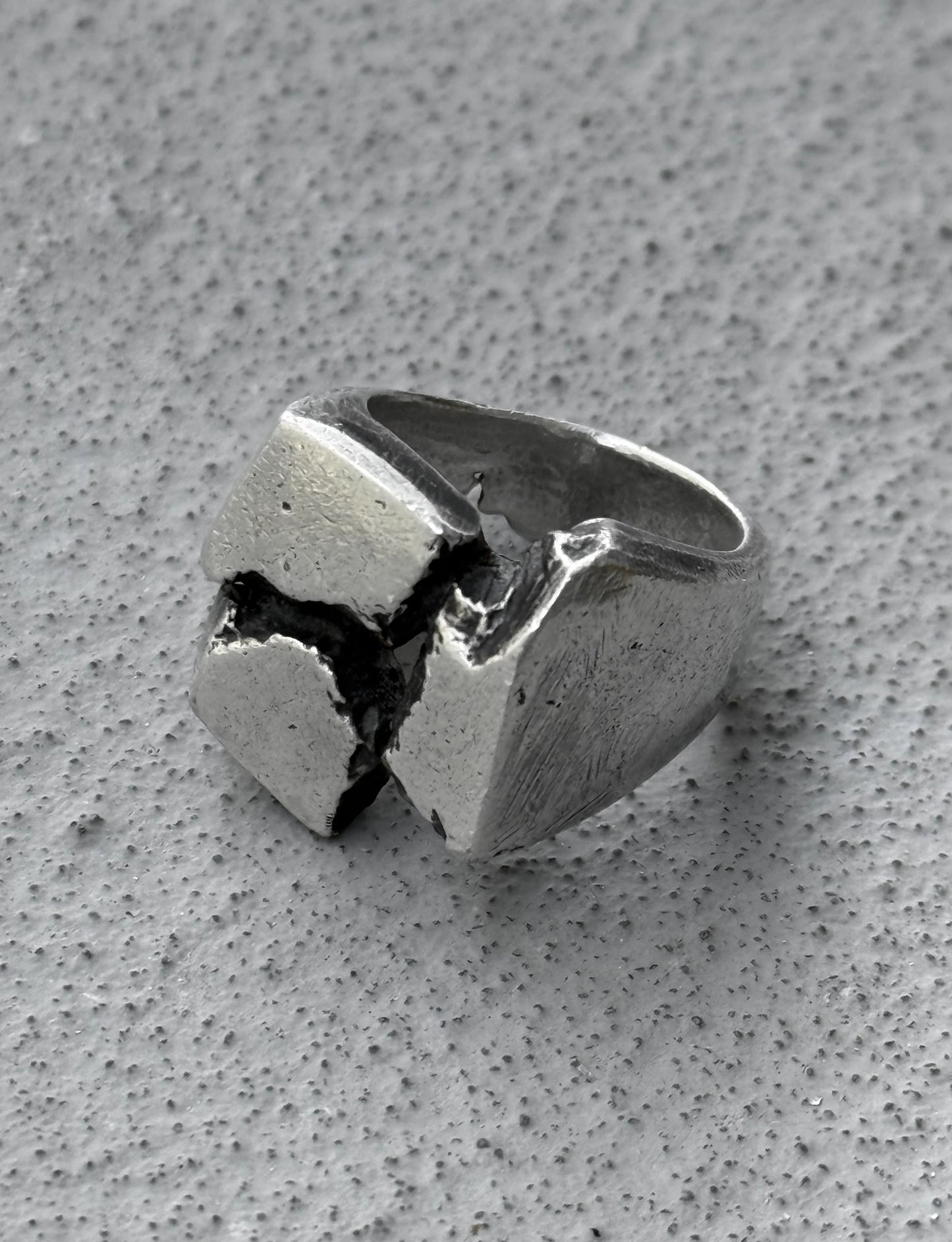 Silver ring with a unique design on a gray surface