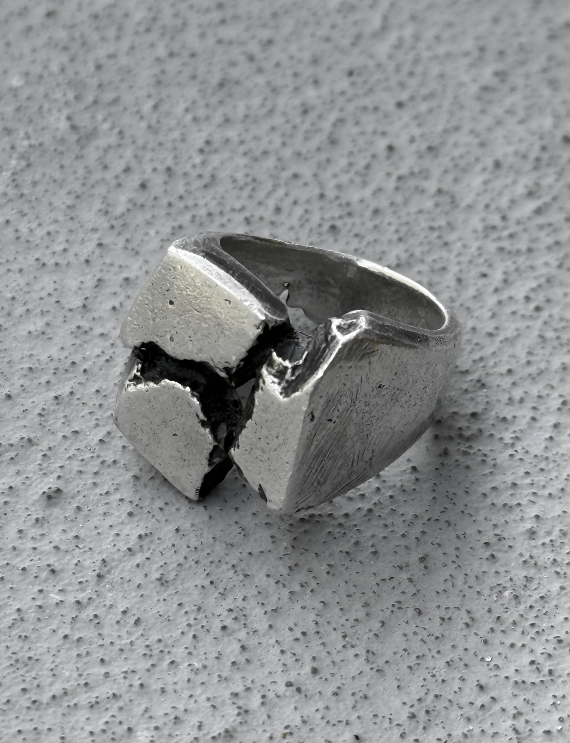 Silver ring with a unique design on a gray surface