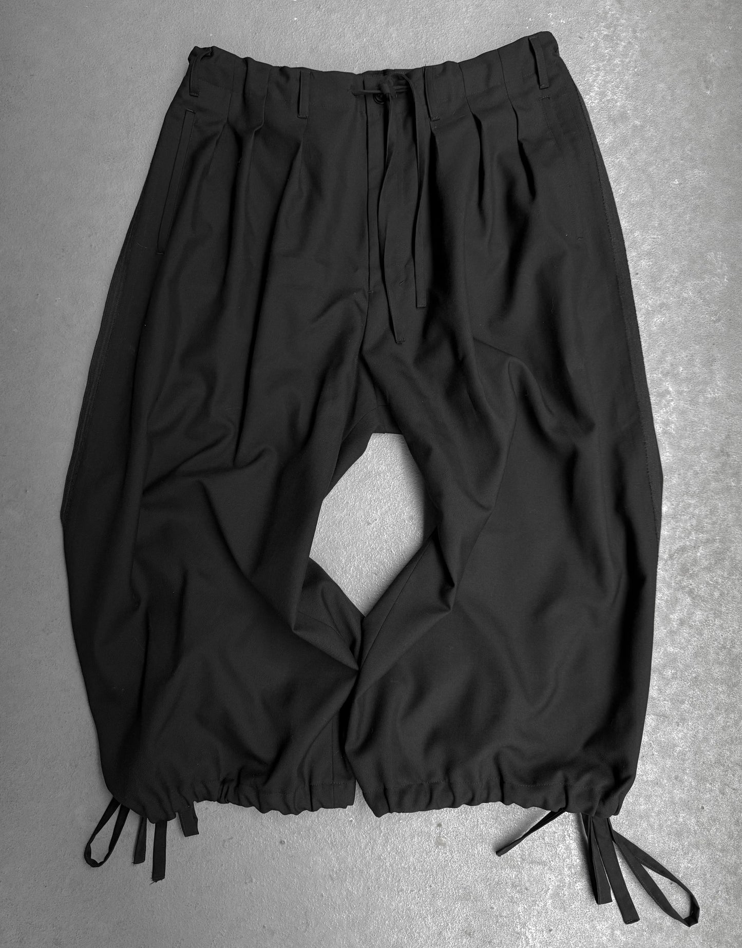 Black pants with drawstrings on a gray background
