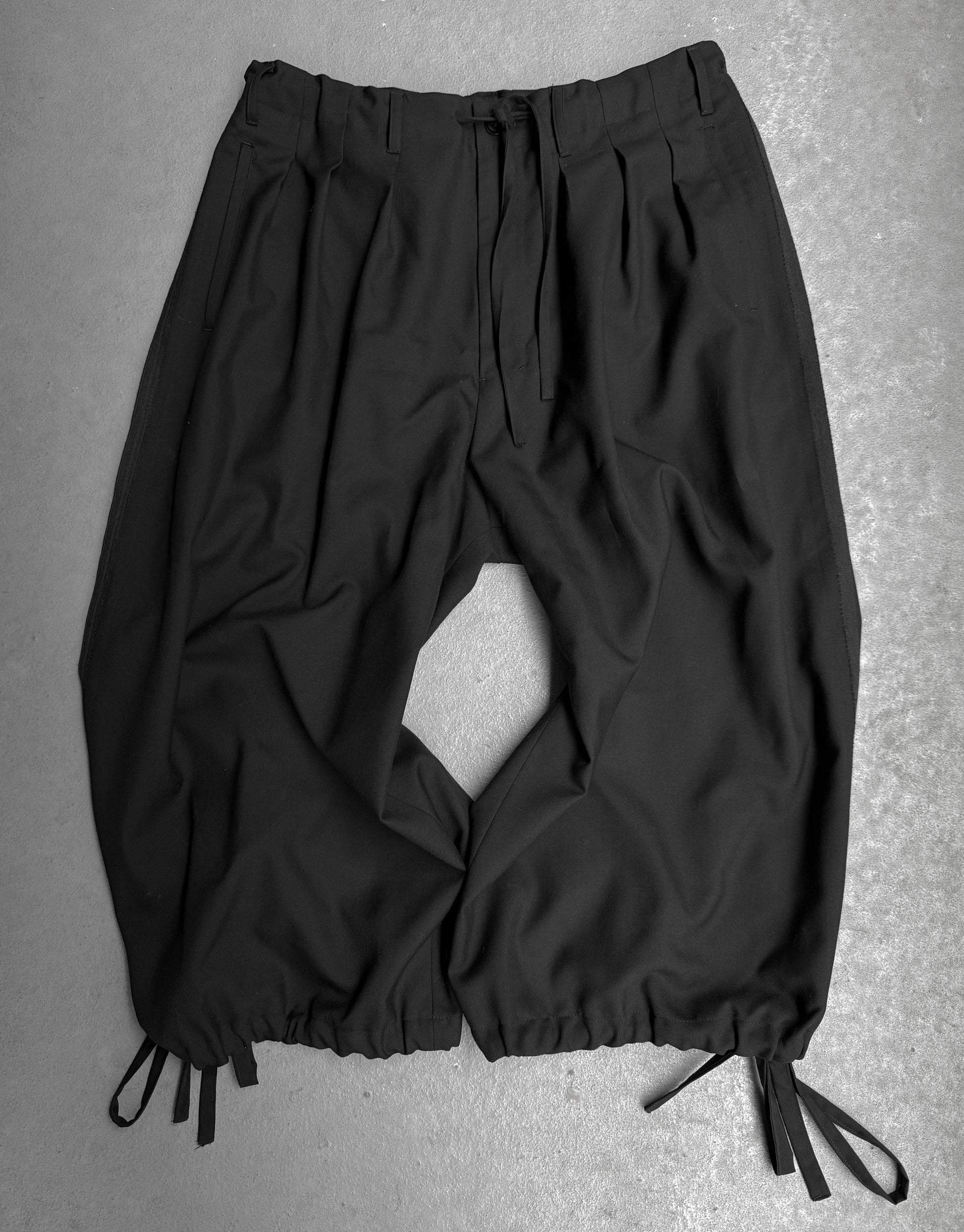 Black pants with drawstrings on a gray background