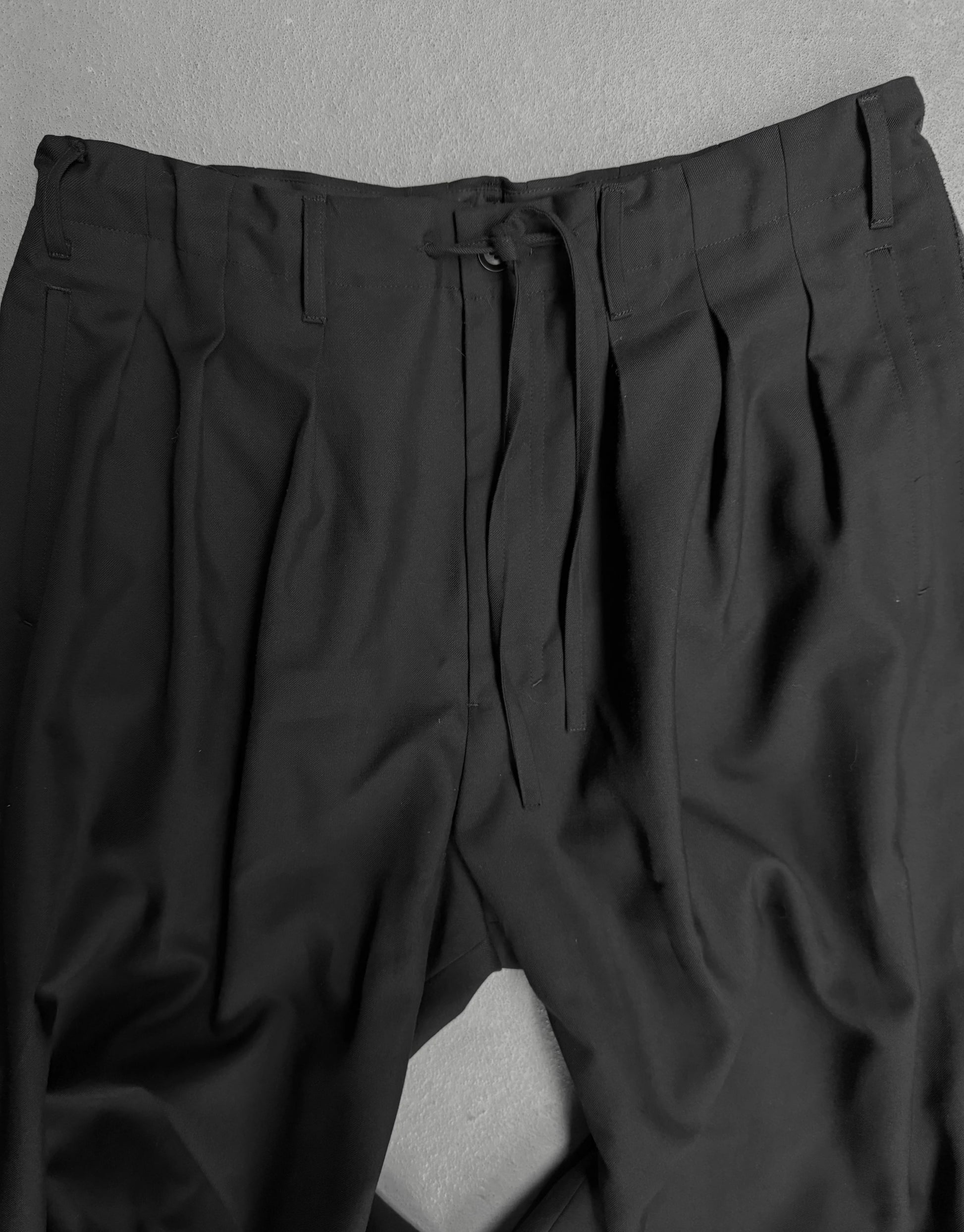 Black pleated pants on a gray background