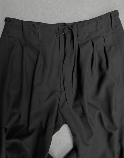Black pleated pants on a gray background